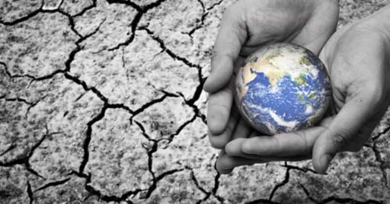 Hands holding Earth against cracked dry ground, symbolizing global water crisis and the need for Rostfrei liquid storage tank solutions